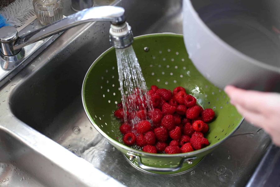 Rinsing raspberries under a kitchen faucet